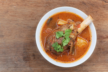 lamb knuckle stew with vegetables on wooden background