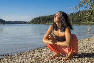 Glückliche Yogine genießt Abendsonne beim Yoga mit Meditation