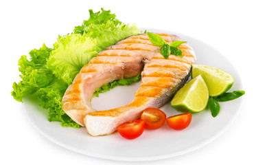 Tasty grilled salmon with tomato and lime on plate close up