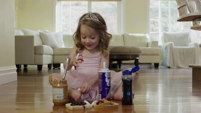 Medium shot of ballerina girl eating whipped cream on floor / Cedar Hills, Utah, United States