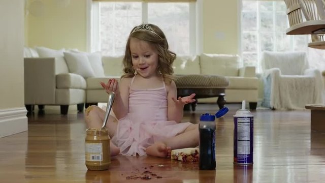 Medium shot of ballerina girl spreading food on floor / Cedar Hills, Utah, United States