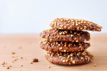 Some tasty oat cookies with nuts, sesame and chocolate lie in a white bowl on a wooden background.