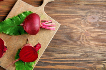 Young beets with leaves on wooden table close up