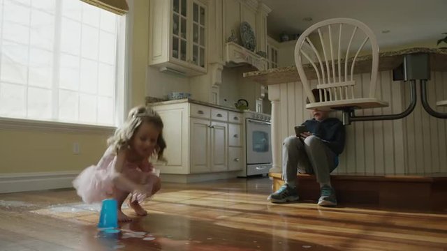 Low angle panning slow motion shot of girl dropping cup on kitchen floor / Cedar Hills, Utah, United States