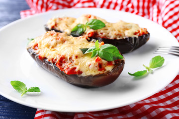 Dish of eggplant with cherry tomatoes and cheese in white plate on red napkin, closeup