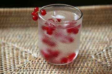 Glass of cold refreshing summer drink with berries and ice cubes on table close up