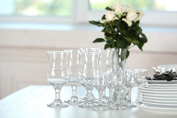 Clean plates, glasses and cutlery on white table