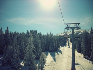 Beautiful snowy winter landscape in a mountain ski resort, with chair lift and ski runs, on a sunny afternoon. Image filtered in faded, retro, Instagram style. - 91092312