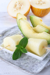 Melon ice lolly on wooden table, closeup