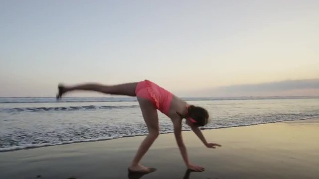 Slow motion wide tracking shot of girl doing cartwheel on beach / Esterillos, Puntarenas, Costa Rica