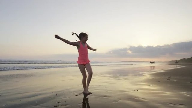 Slow motion wide panning shot of girl doing cartwheel on beach / Esterillos, Puntarenas, Costa Rica