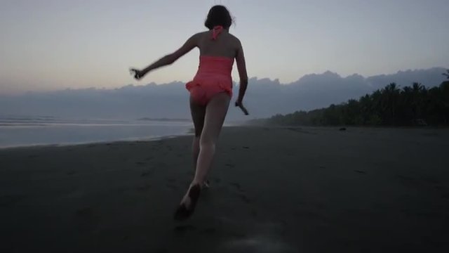 Wide tracking shot of girl doing cartwheel on beach / Esterillos, Puntarenas, Costa Rica