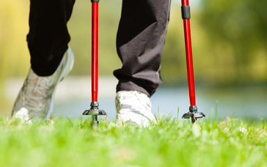 Fototapeta premium Nordic walking. Female legs hiking in the park.