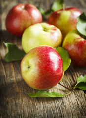 Organic fresh apples with leaves on wooden background