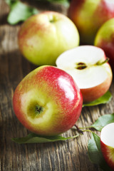 Fresh organic apples with leaves on wooden background