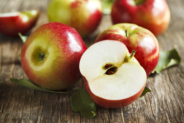 Fresh organic apples with leaves on wooden background