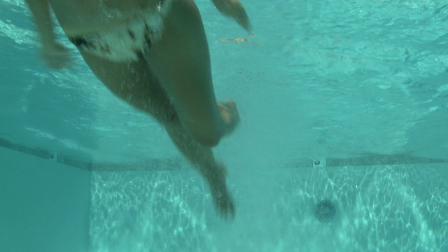 woman in a bikini diving into a swimming pool