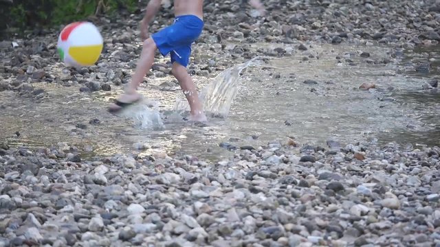 ni&ntilde;o dando toques a bal&oacute;n de playa en r&iacute;o