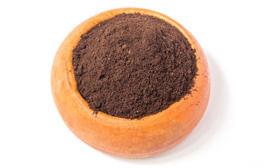 Coffee grounds in a brown pottery cup on white background.