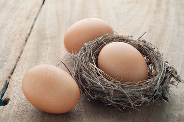 Three eggs on wooden floors and nest.