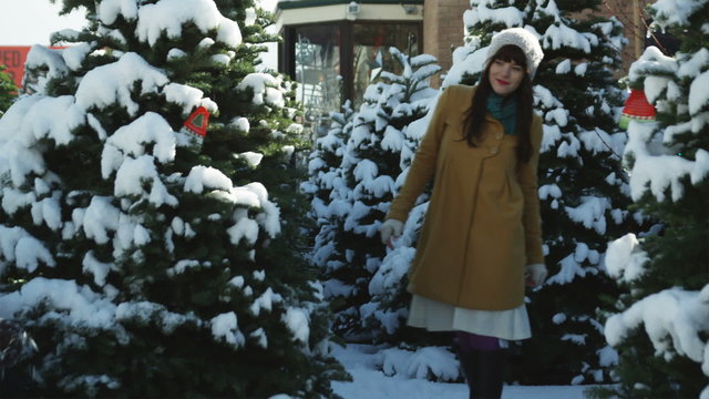 young couple having a snowball fight in a grove of pine trees