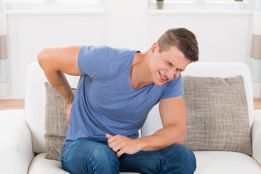 Man On Sofa Suffering From Backpain