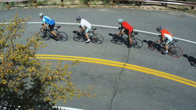 pack of cyclists climbing uphill