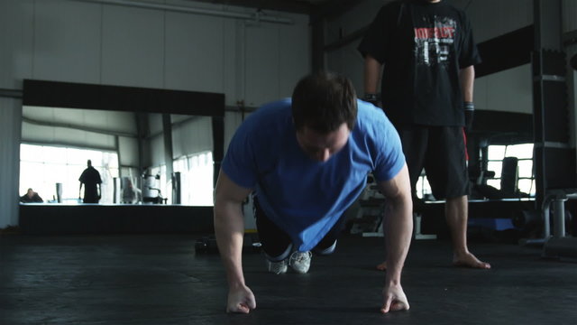 man doing pushups while his trainer motivates him