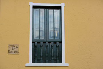 Sign on colonial yellow wall with window details, Bogota