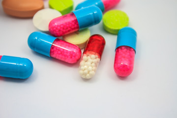 Colored pills, tablets and capsules on white background