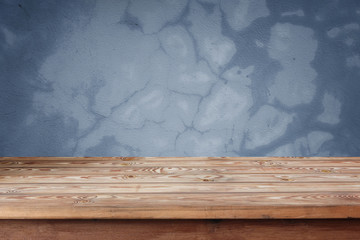 Empty wooden table against a blue wall.