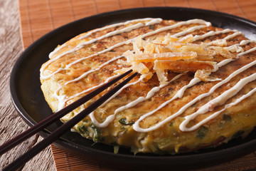 Japanese pizza: okonomiyaki on a plate and chopsticks. horizontal 
