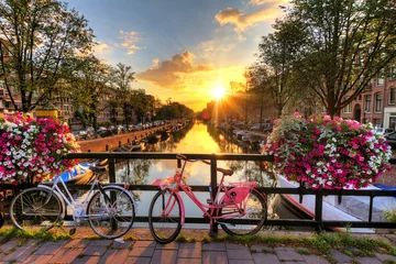 Foto op Plexiglas Amsterdam Mooie zonsopgang boven Amsterdam, Nederland, met bloemen en fietsen op de brug in de lente
