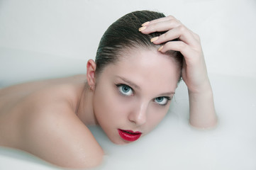 Naklejka premium Fashion portrait of young woman floating in Spa filled with milk
