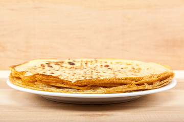 Pancakes in the plate on a wooden background