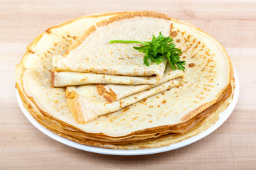 Pancakes in the plate on a wooden background