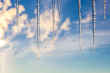 Icicles against a blue sky with clouds