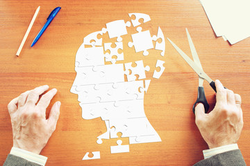 Man gathers a human head as puzzles on the wooden desk