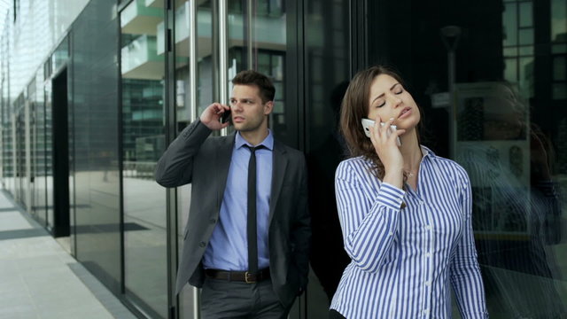 Businesspeople standing in the queue and talking on cellphones, steadycam shot
