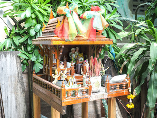 brown spirit house in Thailand with flowers in a vase