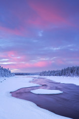 Obraz premium Sunrise over river rapids in a winter landscape, Finnish Lapland