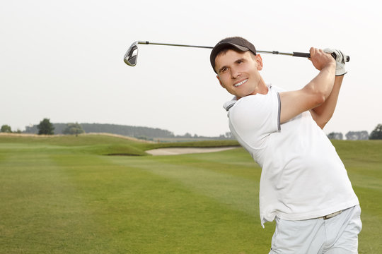 Golfer swinging his niblick out on the course