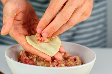 Man hands making dumplings with meat