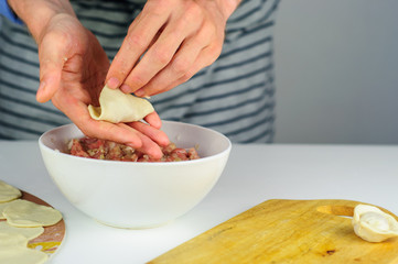 Man hands making dumplings with meat