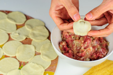 Man hands making dumplings with meat