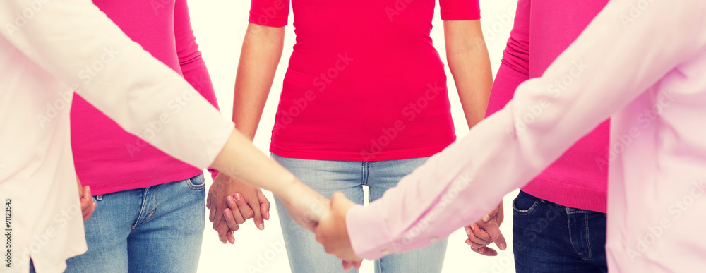 Wall mural close up of women in pink shirts holding hands