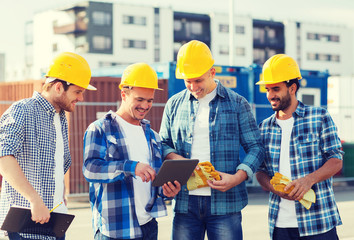 group of smiling builders with tablet pc outdoors