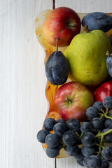 Basket full of fruits. Pear, apple, grape and plum