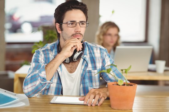 Thoughtful man with hand on chin sitting in office