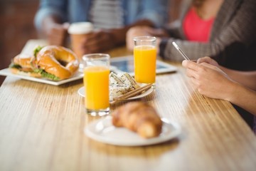 Cropped image of woman using phone during breakfast
